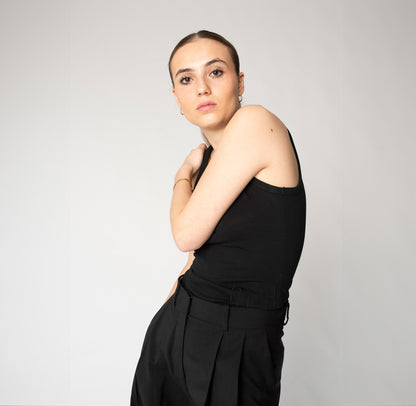 Klassisches Tanktop Schwarz mit minimalistischen, monochromen Logo Stick um die Taille laufend.